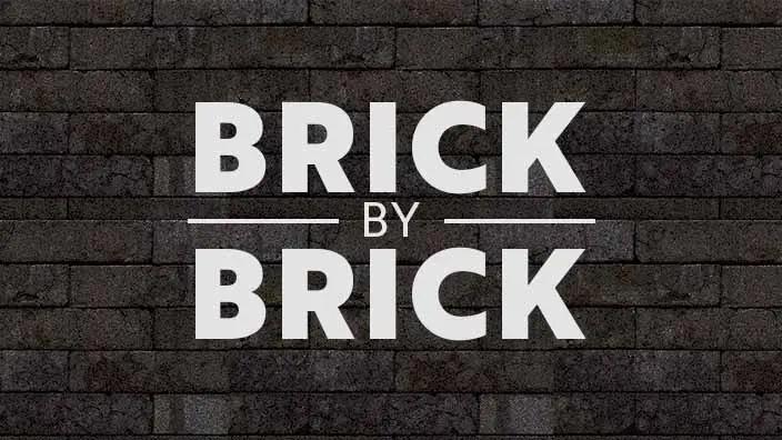 An image of a brick wall with "Brick by Brick" written over it.